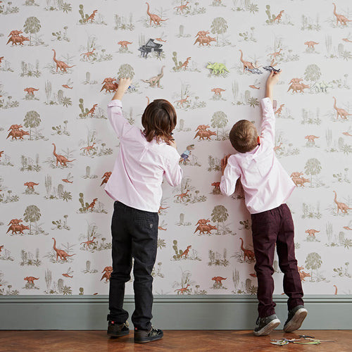 pink and green dinosaurs magnetic wallpaper for children's rooms with two boys playing with magnets on wall surface