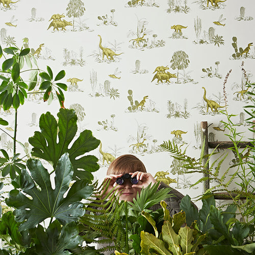 Boy playing amongst plants in front of green dinosaur wallpaper by Sian Zeng 