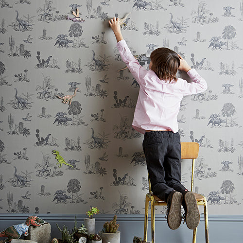 Grå dinosaurier magnetiska tapeter i barns sovrum med pojke som leker med magneter på väggytan